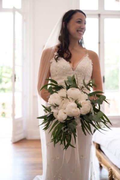 Bride standing interior room ready holding bouquet and smiling white roses flowers